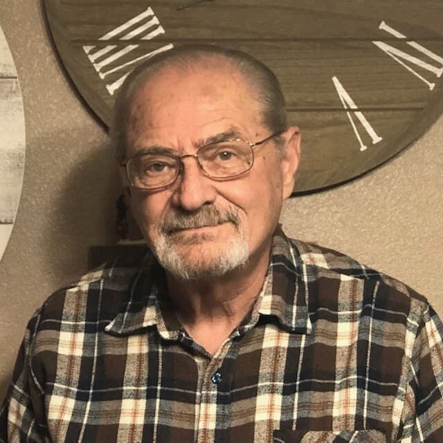 A man with glasses and a beard wearing a plaid shirt.